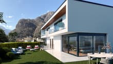 Modern white villa with large windows, patio with outdoor furniture, terrace, and mountain view.