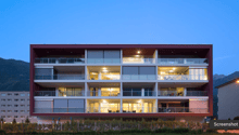 Modern multi-story residential building, multiple balconies, mountain view