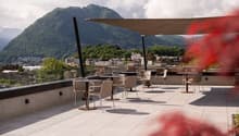 A terrace with a canopy, chairs, tables, surrounded by plants, views of the mountains