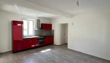 Empty kitchen with red cabinets, gray tiled floor, white walls, window, stove, sink, and a lamp