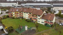 Apartment complex with yellow exterior walls, brown roofs, balconies, and playground in the front.