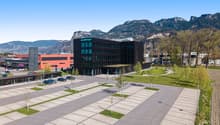 modern office building, green rooftop, parking lot, trees, cars parked, mountains in the background