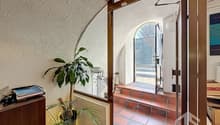 open door, arched window, red tiled floor, plants, wooden cabinet, open door leading to outside