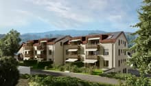 Three story residential building, solar panels, white and brown walls, balconies, fenced garden