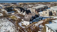 Aerial view of a row of houses with snow on the ground, near the sea