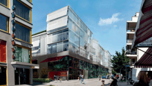 Modern building with glass facade, red awning, green roof, multiple floors, urban setting