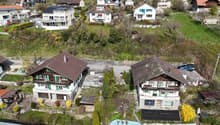 Swiss-style houses, brown roofs, green shutters, surrounded by greenery, driveways, solar panels on some roofs