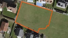 Plot of land with an area of 1,000 square meters, surrounded by houses and greenery.