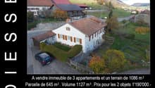White house with brown roof, car parked, garden, green field, mountains in the distance