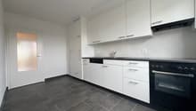 modern kitchen with white cabinets, black countertops, integrated dishwasher, washing machine, oven, sink, faucet