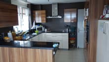 modern kitchen with wooden cabinets, black granite countertops, white appliances, tiled floor, window