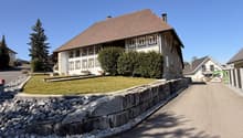 2 story house, brown roof, white walls, multiple windows, stone wall, driveway, green lawn, trees