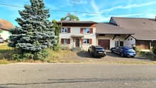 Detached house, two storeys, brown roof, white walls, wooden door, brown garage doors, trees, parking for two cars.