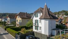 3 story house, white exterior, brown roof, green shutters, car parked in front, garden, hedges, neighboring houses
