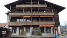 3-story wooden chalet-style building with balconies, decorative wooden trim, and awnings