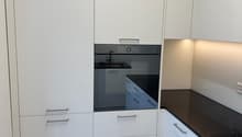modern kitchen with white cabinets, black countertops, built-in oven, wooden floor