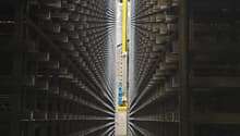 Industrial facility with large metal shelving units, yellow automated retrieval system, and a central aisle