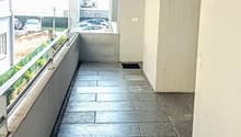 Hallway with tile flooring, white walls, and a balcony or terrace visible through the windows.