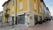 Yellow building, multiple windows, brick floor, black iron gate, balcony
