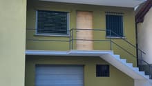 2 story house, yellow exterior, metal railings, wooden door, garage, balcony