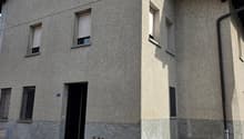 2 story house, gray exterior, multiple windows, entrance with steps, small potted plant