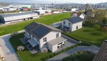 Two-story house with solar panels, a garage, outdoor seating area, garden, swimming pool, and a nearby small house.