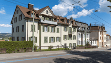 3 story building, brown roof, green shutters, balconies, street view