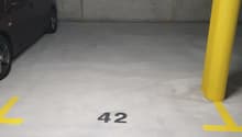 underground parking lot, with grey floor, white walls, yellow lines, car parking spot