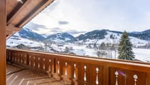 balcony with wooden railing, snowy mountain background, sunlight