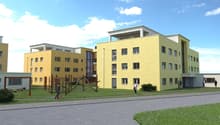 3 story building, yellow paint, white roof, balconies, large windows, play area, sidewalk, lawn, two people walking