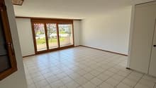 large empty room, large sliding windows, tiled floor, wooden doors