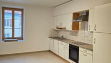Modern, clean kitchen with white cabinetry, a tile backsplash, wooden flooring, and stainless steel appliances.
