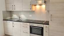 modern kitchen with wooden cabinets, black countertops, stainless steel appliances, tiled floor