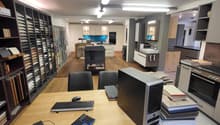 A room with desks, computers, keyboards, mice, and chairs.