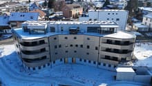 Curved, multistory building, with multiple balconies, large windows, and rooftop solar panels