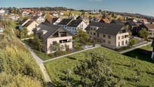 New town area with several modern townhouses surrounded by greenery, paths, and a playground.