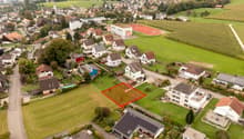 Suburban neighborhood with various sized houses, one empty plot marked with red rectangle, houses have various features like garages and solar panels