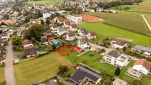 aerial view of a residential area, with various houses, solar panels, and a tennis court.