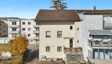 white apartment building, balconies, brown roof, multiple windows, chimneys