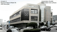 4-story office building with a modern, glass and concrete facade. The building is located on Rue de la Pierre à Mazel 39 in Neuchâtel, Switzerland and is part of the Innoparc 4 complex. There are several cars parked in front of the building.