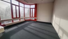 Empty room with large windows and grey carpet.