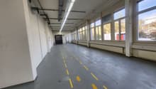 industrial warehouse, white walls, yellow painted lines on floor, tall windows, two doors on left