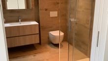 Bathroom with wooden floor, glass shower, wooden vanity, toilet, mirror