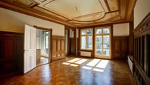 large room, wooden parquet flooring, wooden paneling, wooden ceiling with intricate design, double doors, windows with grills