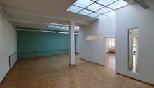 Empty room with wooden floor, white walls, glass windows, and ceiling lights
