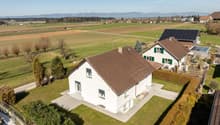 modern white house, brown roof, solar panels, large garden, driveway, surrounded by fields