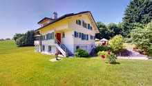 2 story house, yellow, white windows, blue shutters, red door, stairs to entrance, paved driveway, garden, flower pots, fence, small gazebo