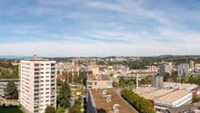 cityscape of a town with multiple buildings, trees, hills in the background
