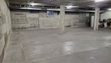 Large empty concrete floor, two pillars, small open window, metal beams