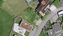 Aerial view of house and adjacent area. Plot with numbers on sides, house with solar panels on the roof.